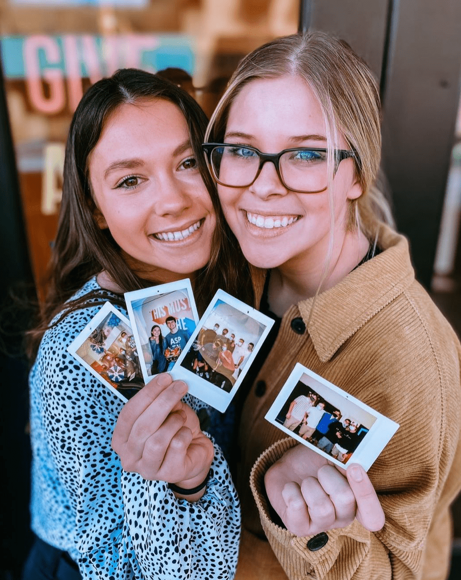 two women holding polaroid pictures