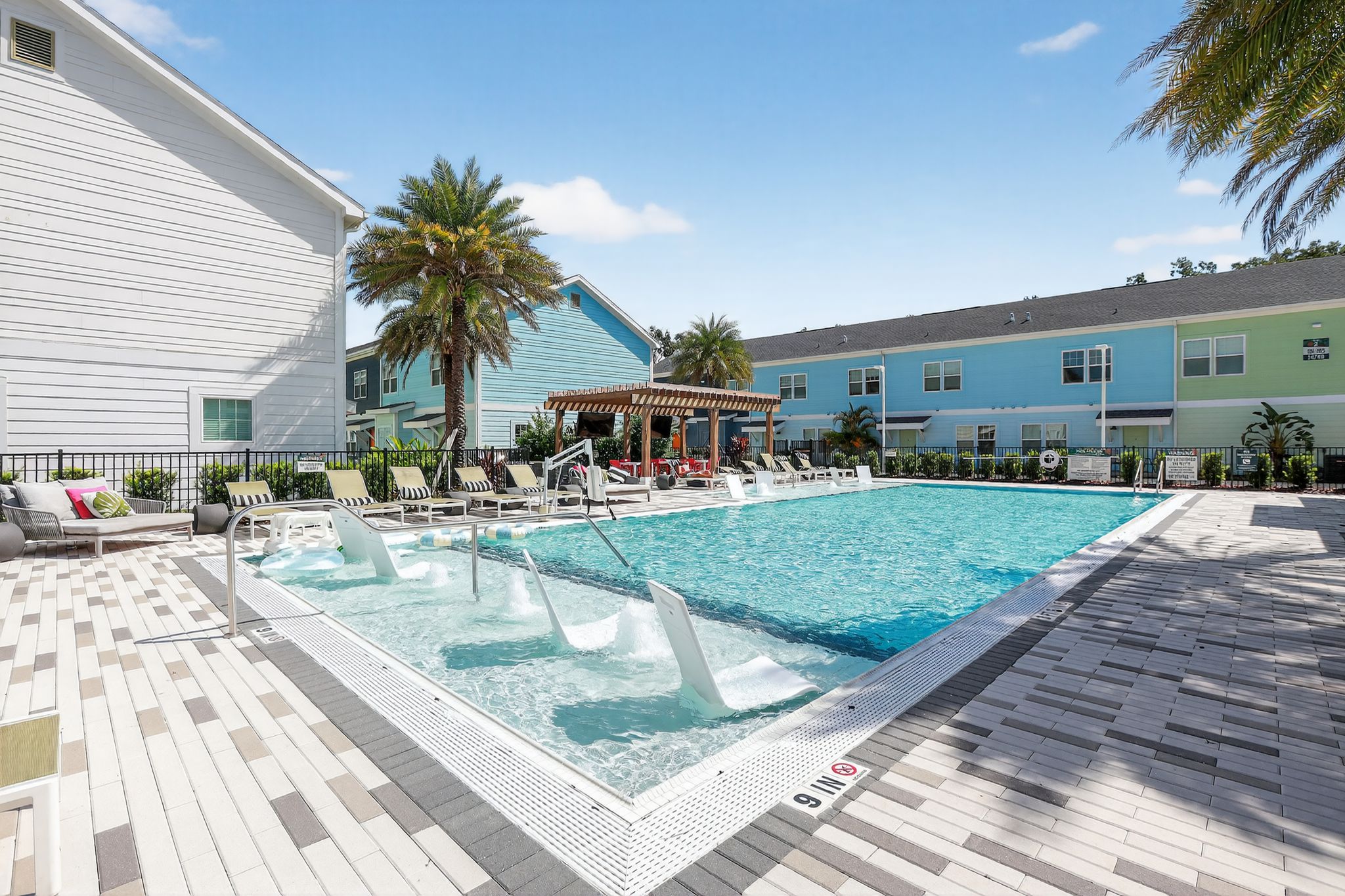 Modern pool with lounge chairs and palm trees.